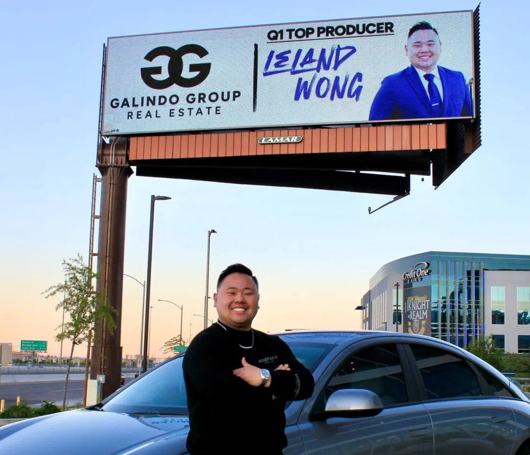 Leland Wong in front of a Galindo Group Real Estate billboard